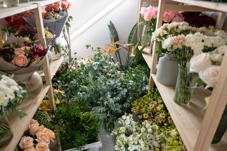 Flower shop concept. Different varieties fresh spring flowers in refrigerator room for flowers. Bouquets on shelf, florist business.の写真素材