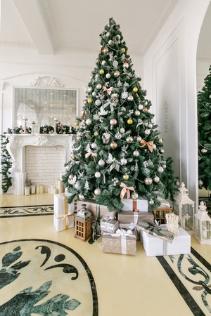 Presents and Gift boxes under Christmas Tree. Beige boxes with ribbon bow. New year decorated house interior. Winter Holiday concept.の写真素材