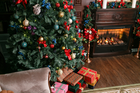 Presents and Gift boxes under Christmas Tree. Colorful boxes with ribbon bow. New year decorated house interior. Winter Holiday concept.の写真素材
