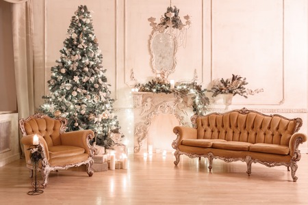 Christmas tree, garlands, candles,lanterns, gifts in the evening. classical interior of a white room with a decorated fireplace, sofa,の写真素材