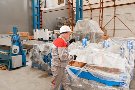 manufacture workshop. Worker unpacks the machine in the warehouse. the production of ventilation and...