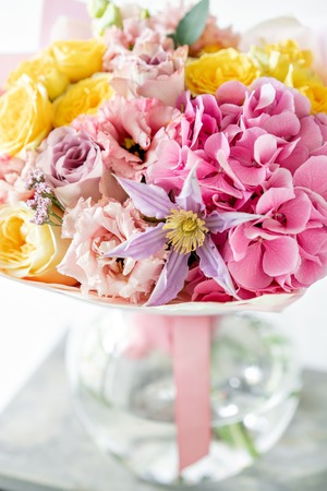 beautiful spring bouquet. flowers arrangement with various of colors in glass vase on old table. bright room, white wall. copy spaceの写真素材