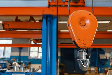 Crane hook. The system of pulleys and ropes, a hanging mechanism in the production area. Movement remote control pendant switch for overhead crane in the factoryの写真素材