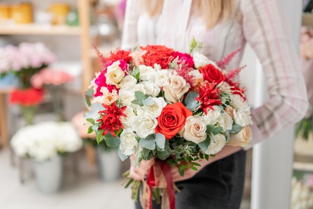 beautiful spring bouquet. Young girl holding a flowers arrangement with red and white colorsの写真素材