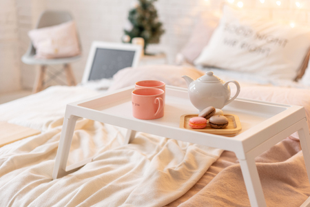 breakfast in bed, tray with cup of coffee and macaroon. Modern bedroom interior. Romantic morning surprise.の写真素材