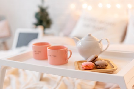 breakfast in bed, tray with cup of coffee and macaroon. Modern bedroom interior. Romantic morning surprise.の写真素材
