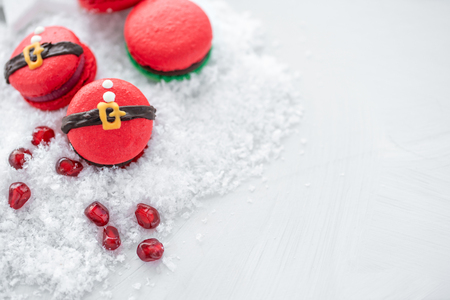 Funny cookie in the form red santa belly on gray table sprinkled with snow. Modern european French cuisine. Christmas theme, Merry Christmas card. New year mood. Variety of sweet macaroons. copy spaceの写真素材