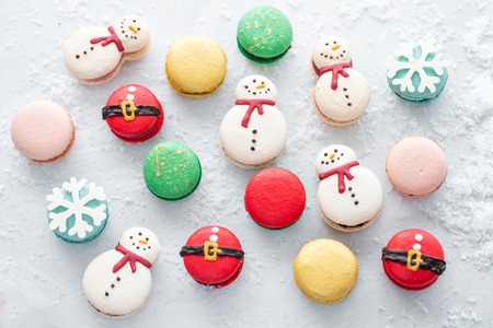 Variety of sweet macaroons on gray table sprinkled with snow. Modern european French cuisine....