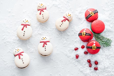 Variety of sweet macaroons. Cookie in the form of a snowman and red santa on gray table sprinkled with snow. Modern european French cuisine. Christmas theme, Merry Christmas card. New year mood.の写真素材