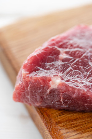 Morning in the kitchen. Raw meat. Raw fresh beef steak on a wood cutting board. White wooden background, top view, copy space, Daylightの写真素材