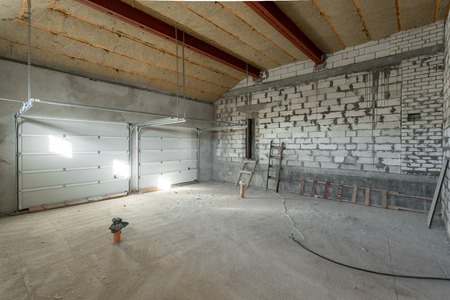 Large garage for two cars with of the gate. overhaul and reconstruction. Working process of warming inside part of roof. House or apartment is under construction, remodeling, renovation, restoration.の写真素材