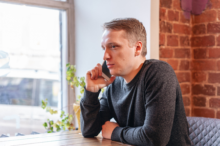 Man talking on the phone. Freelancer work in modern coworking. Programmer at remote job. Successful people, businessman in comfortable cafe. High large Windowsの写真素材