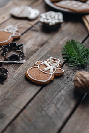 Cookies in the form of snowman Christmas winter morning. Woman draws Icing on honey gingerbread...