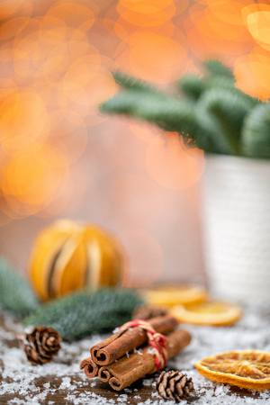 Cinnamon sticks and orange slicesChristmas arrangement with Norwegian pine Nobilis and decorated with toys. Garland bokeh on background. Dark wooden table sprinkled with snowの写真素材