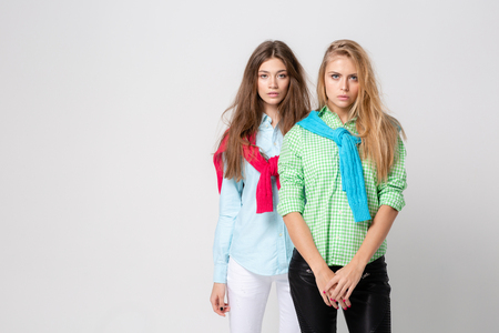 happy girlfriends women in shirts and a sweater on his shoulders. Fashion spring image of two sisters. Colorful colors clothes. Models with Blonde and light brown hair.の写真素材