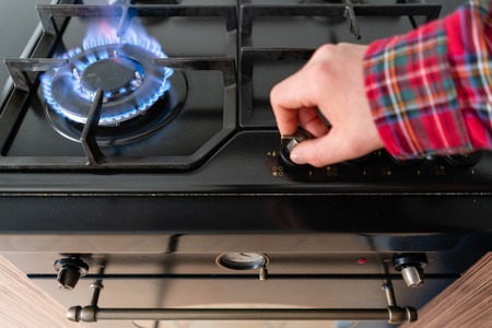 focus on fire. A man lighting the gas-stove with by means of automatic electric ignition. Modern gas...