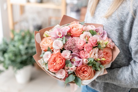 beautiful fresh cut bouquet of mixed flowers in woman hand. the work of the florist at a flower shop. Delicate Pastel tones colorの写真素材