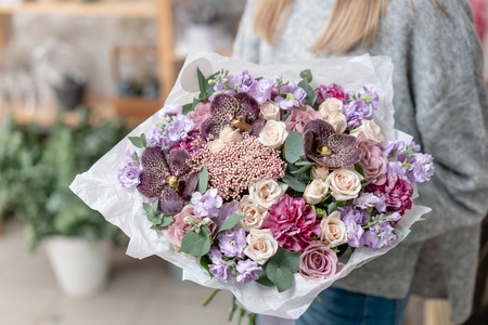 beautiful fresh cut bouquet of mixed flowers in woman hand. the work of the florist at a flower shop. Delicate Pastel tones colorの写真素材
