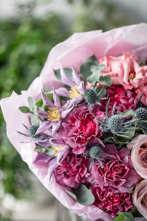 beautiful fresh cut bouquet of mixed flowers in vase on wooden table. . the work of the florist at a flower shop. Delicate Pastel tones colorの写真素材