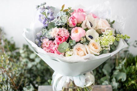 beautiful fresh cut bouquet of mixed flowers in vase on wooden table. The work of the florist at a flower shop. Delicate Pastel tones colorの写真素材