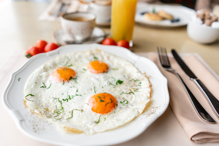 Fried egg. Close up view of the fried egg on a white plate. Light morning Breakfast, fresh warm pastries and aromatic cappuccino coffeeの写真素材