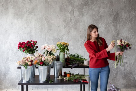 Florist workplace. Woman arranging a bouquet with roses, chrysanthemum, carnation and other flowers. A teacher of floristry in master classes or coursesの写真素材