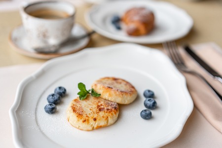 Cottage cheese pancakes or syrniki with blueberry on white plate, closeup view. Russian, Ukrainian cuisine. Healthy tasty breakfastの写真素材