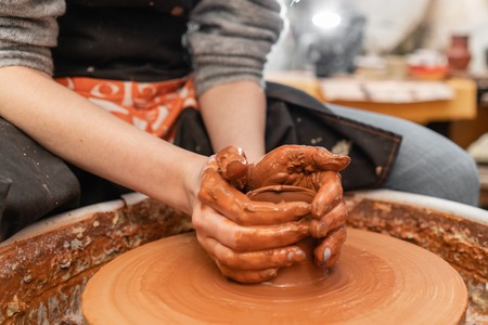 Craftsman hands making pottery bowl. Woman working on potter wheel . Family business shop sculpts pot from clay view top.の写真素材