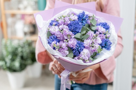 Bouquets of blue hyacinths and matthiola of lilac color in woman hand. Spring flowers from Dutch gardener. Concept of a florist in a flower shop. Wallpaper.の写真素材