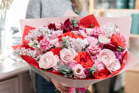 beautiful fresh cut bouquet of mixed flowers in woman hand. the work of the florist at a flower shop. Red and pink colorの写真素材