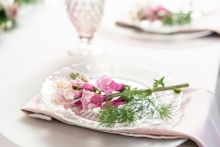 Closeup Table setting with plates and tableware, adorned with flowers. Floral decoration for wedding...