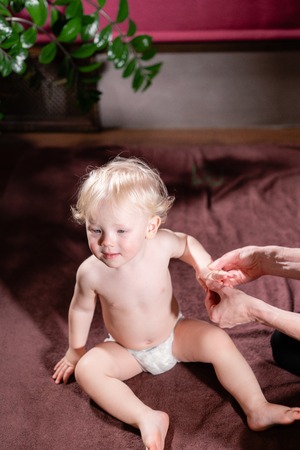 Baby massage. Mother or therapist makes hand massage to her baby at home. Health care and medicine concept. Blond boyの写真素材