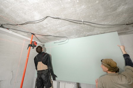 drywall installation, wall alignment. Laser measurement during renovation. Construction tools and equipment. Red laser light lines for level measure.の写真素材