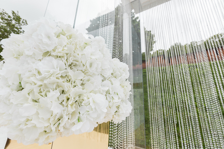 Crystal decorations for the wedding ceremony, luxurious decor. Beautiful arch decorated with chains with transparent beads on the background green lawnの写真素材