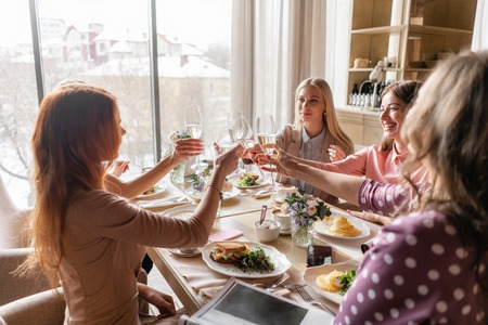 four women. Portrait of young people having breakfast at table in restaurant. Champagne for Breakfast. Talk and laugh, live communicationの写真素材