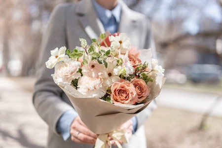 beautiful fresh cut bouquet of mixed flowers in woman hand. the work of the florist at a flower shop. Delicate Pastel tones colorの写真素材