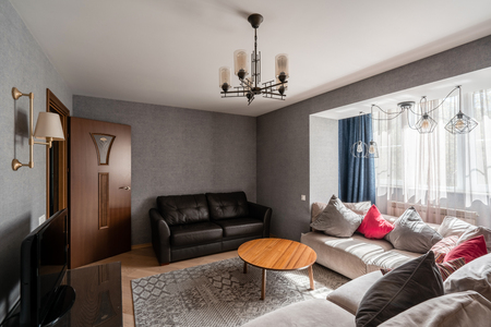 Russia, Nizhny Novgorod - April 26, 2019: Private apartment. Modern living room with Leather sofa, armchair, wooden coffee table and Tv. pillows on cozy sofa and lamps. Interior designのeditorial素材
