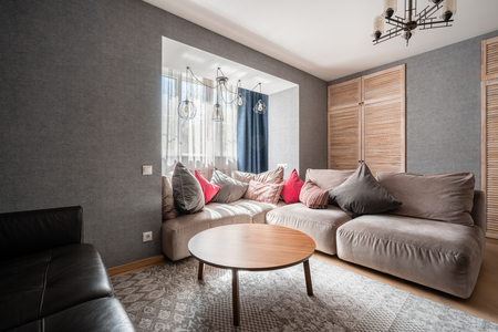 Russia, Nizhny Novgorod - April 26, 2019: Private apartment. Modern living room with Leather sofa, armchair, wooden coffee table and Tv. pillows on cozy sofa and lamps. Interior designのeditorial素材