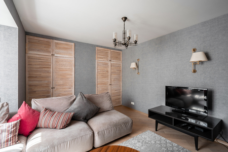 Russia, Nizhny Novgorod - April 26, 2019: Private apartment. Modern living room with Leather sofa, armchair, wooden coffee table and Tv. pillows on cozy sofa and lamps. Interior designのeditorial素材
