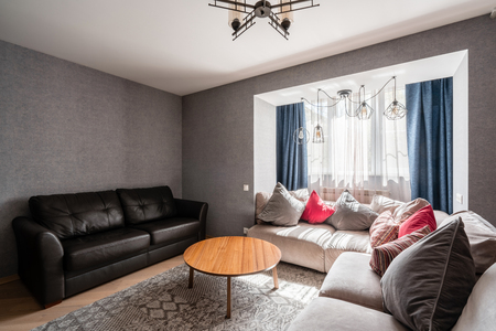 Russia, Nizhny Novgorod - April 26, 2019: Private apartment. Modern living room with Leather sofa, armchair, wooden coffee table and Tv. pillows on cozy sofa and lamps. Interior designのeditorial素材
