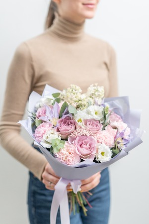 Beautiful bouquet of mixed flowers in woman hand. the work of the florist at a flower shop. Delicate Pastel color. Fresh cut flower. Pink and lilac colorの写真素材