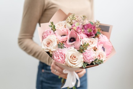 Beautiful bouquet of mixed flowers in woman hand. the work of the florist at a flower shop. Delicate Pastel color. Fresh cut flower. Pink and white colorの写真素材