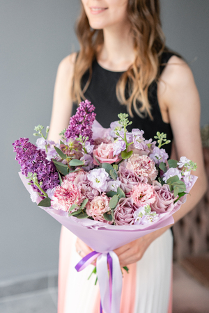 Flower shop. Beautiful bouquet of mixed flowers in woman hand. the work of the florist at a flower shop. Delicate Pastel color. Fresh cut flower. Pink and lilac colorの写真素材