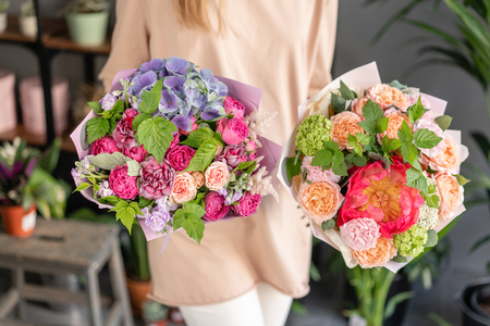 Two Small Beautiful bouquets of mixed flowers in woman hand. Floral shop concept . Beautiful fresh cut bouquet. Flowers deliveryの写真素材