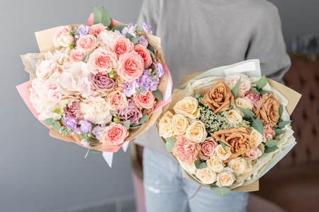 Two Small Beautiful bouquets of mixed flowers in woman hand. Floral shop concept . Beautiful fresh cut bouquet. Flowers deliveryの写真素材