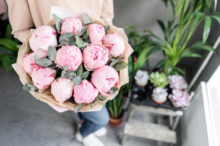 Pink peonies in womans hands. Beautiful peony flower for catalog or online store. Floral shop concept . Beautiful fresh cut bouquet. Flowers deliveryの写真素材