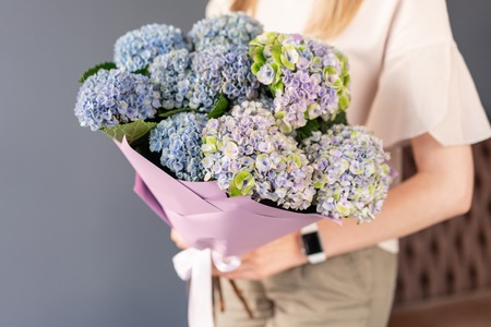 Small Beautiful bouquet of hydrangea flowers in woman hand. Floral shop concept . Beautiful fresh cut bouquet. Flowers deliveryの写真素材