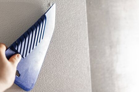 Close-up plastic spatula. Worker glueing wallpapers on concrete wall. Repair the apartment. Home...