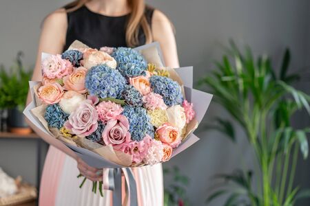 Beautiful bouquet of mixed flowers in woman hand. Floral shop concept . Handsome fresh bouquet. Flowers delivery. Blue and pink colorの写真素材