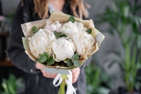 White peonies in womans hands. Beautiful fresh peony flower for catalog or online store. Floral shop concept. Flowers delivery.の写真素材
